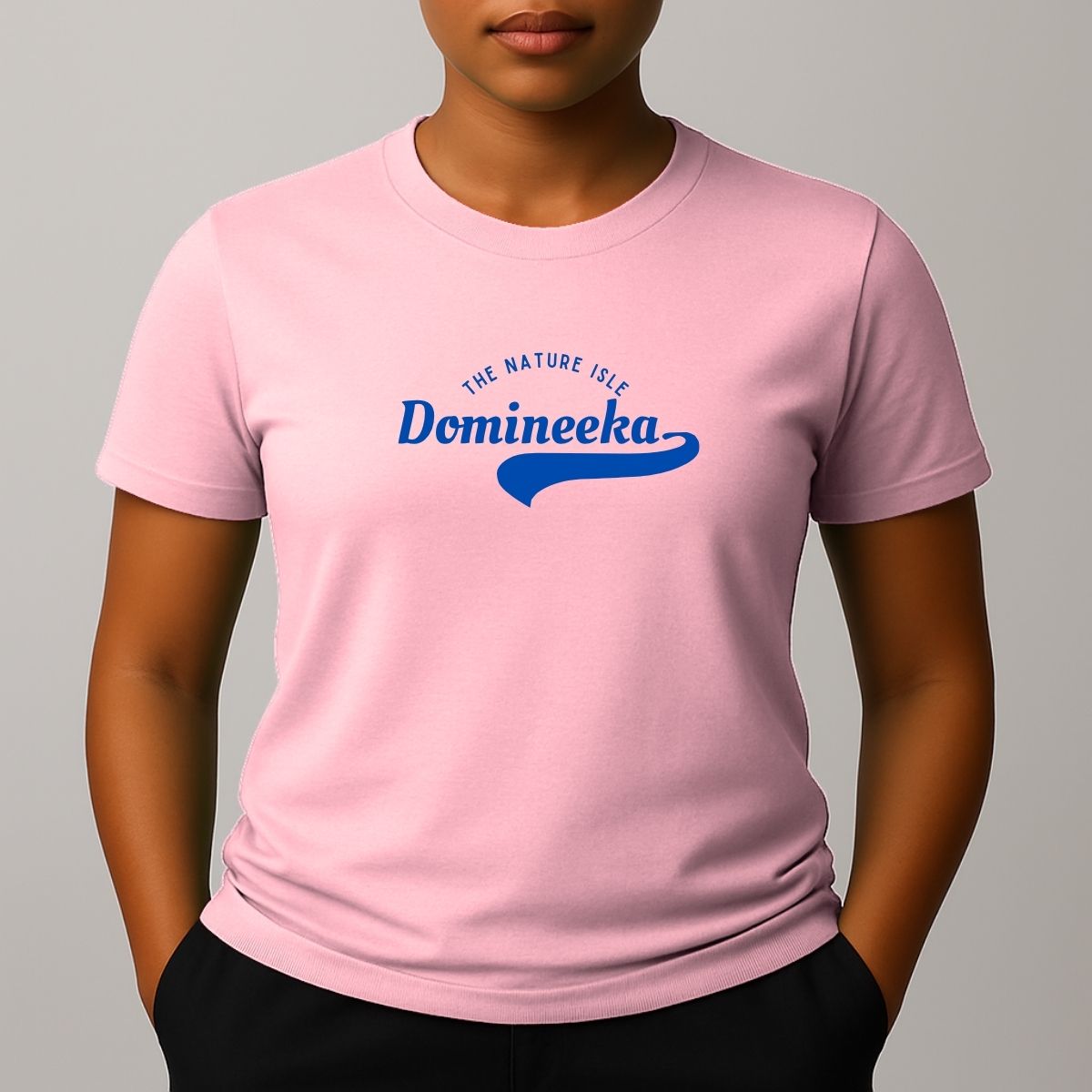 Person wearing a pink t-shirt with a blue graphic print that reads 'THE NATURE ISLE' and a phonetic spelling of 'DOMINEEKA'.