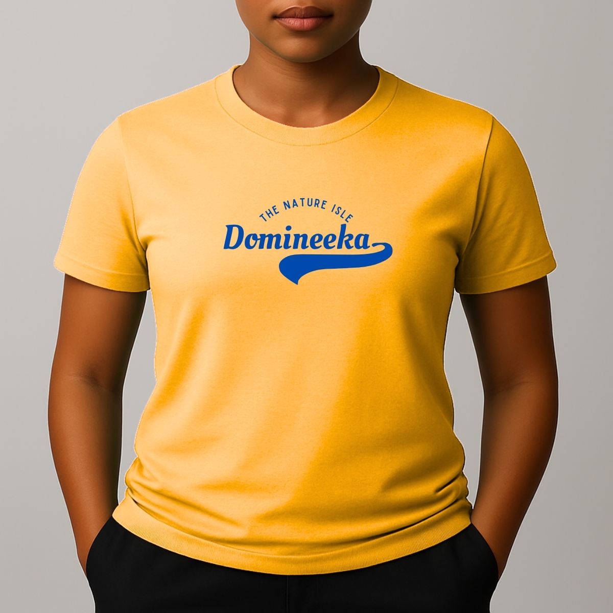 Person wearing a yellow  t-shirt with a blue graphic print that reads 'THE NATURE ISLE' and a phonetic spelling of 'DOMINEEKA'.