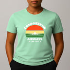 Person wearing a mint green short-sleeve T-shirt with a retro-style graphic reading 'DOMI-NEEKUN AIRWAYS' and 'IND. 1978' over a striped sunset and airplane silhouette.