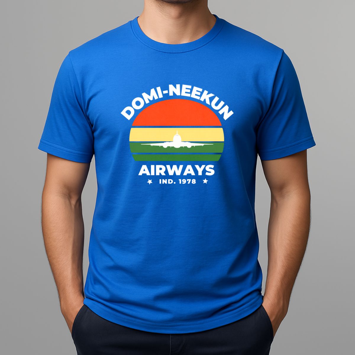 Person wearing a blue short-sleeve T-shirt with a retro-style graphic reading 'DOMI-NEEKUN AIRWAYS' and 'IND. 1978' over a striped sunset and airplane silhouette.