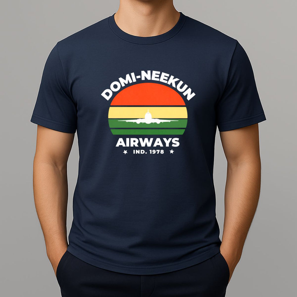 Person wearing a navy short-sleeve T-shirt with a retro-style graphic reading 'DOMI-NEEKUN AIRWAYS' and 'IND. 1978' over a striped sunset and airplane silhouette.