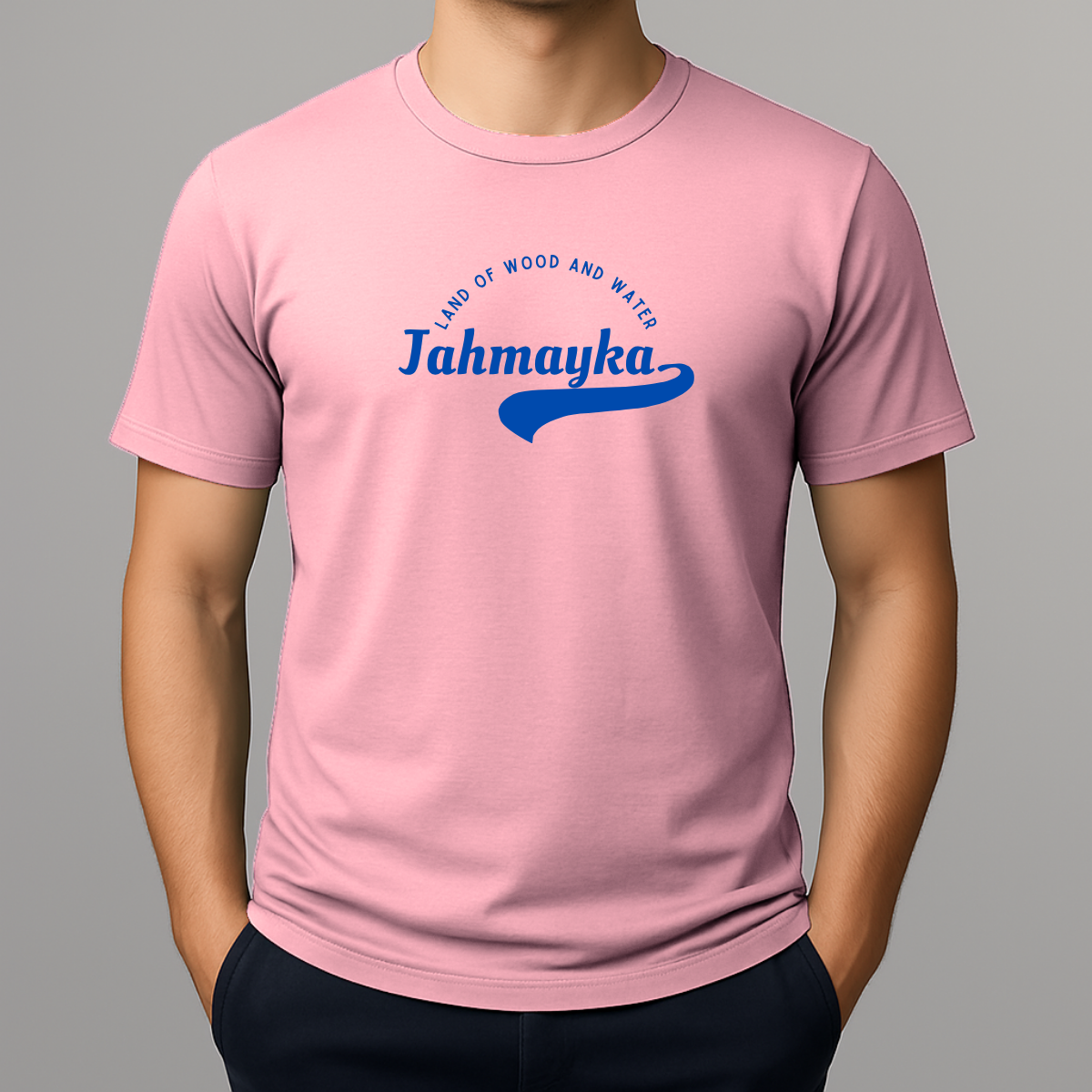 Person wearing a light pink t-shirt with a blue graphic that phonetically spells Jamaica as 'Jahmayka' and 'LAND OF WOOD AND WATER'.