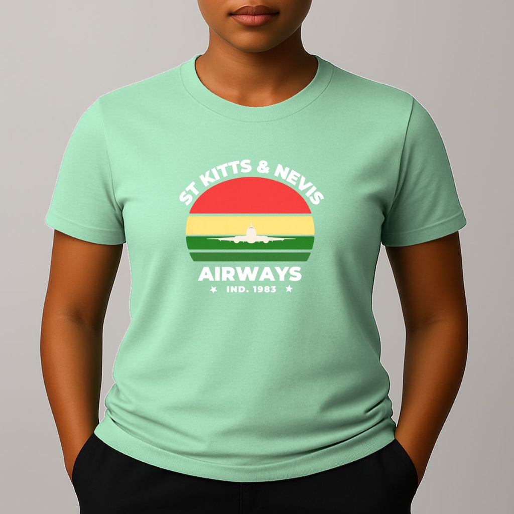 Person wearing a mint green t-shirt with a graphic print on the chest, featuring the text 'ST KITTS & NEVIS AIRWAYS' in white, surrounding a circular flag design with red, yellow, and green horizontal bands and a white airplane silhouette.