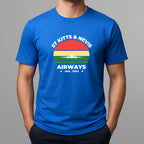 Person wearing a bright blue t-shirt with a graphic print on the chest, featuring the text 'ST KITTS & NEVIS AIRWAYS' in white, surrounding a circular flag design with red, yellow, and green horizontal bands and a white airplane silhouette.