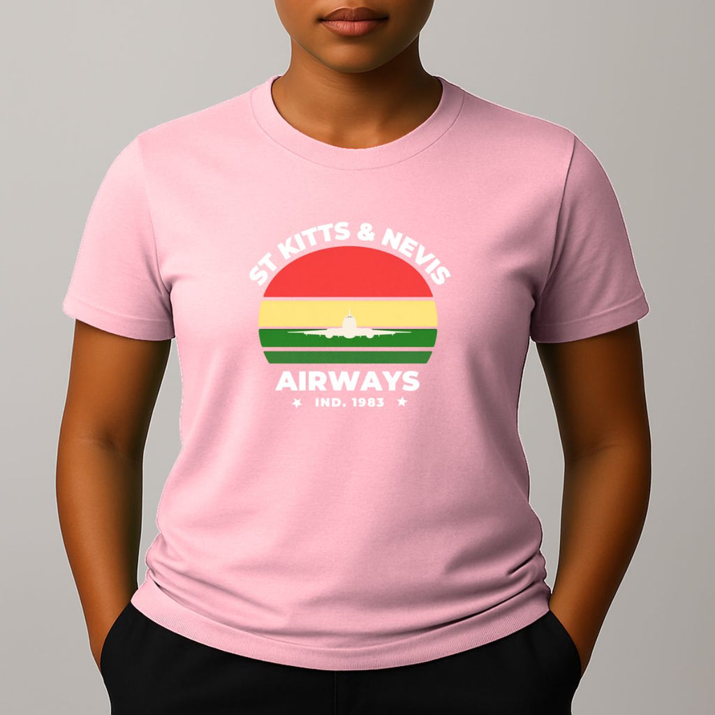 Person wearing a pink t-shirt with a graphic print on the chest, featuring the text 'ST KITTS & NEVIS AIRWAYS' in white, surrounding a circular flag design with red, yellow, and green horizontal bands and a white airplane silhouette.