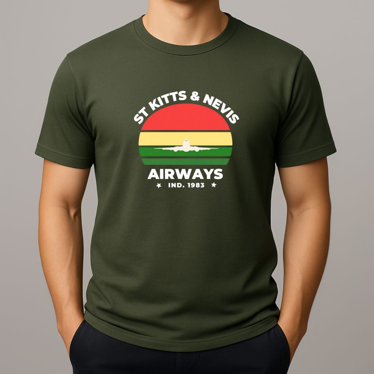 Person wearing a khaki t-shirt with a graphic print on the chest, featuring the text 'ST KITTS & NEVIS AIRWAYS' in white, surrounding a circular flag design with red, yellow, and green horizontal bands and a white airplane silhouette.
