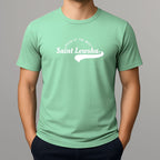 Person wearing a mint green crewneck t-shirt with a white graphic that reads 'Saint Lewsha' and 'HELEN OF THE WEST' on the chest.