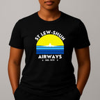 Person wearing an black t-shirt with a graphic print that reads 'ST LEW-SHUN AIRWAYS IND. 1979' in white, above and below a colourful striped circle with a white airplane in the center.