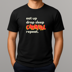 Person wearing a black t-shirt with a colorful graphic text in white, blue and red that reads 'eat up drop sleep CARNIVAL repeat.'