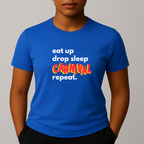 Person wearing a blue t-shirt with a colorful graphic text in white, blue and red that reads 'eat up drop sleep CARNIVAL repeat.'